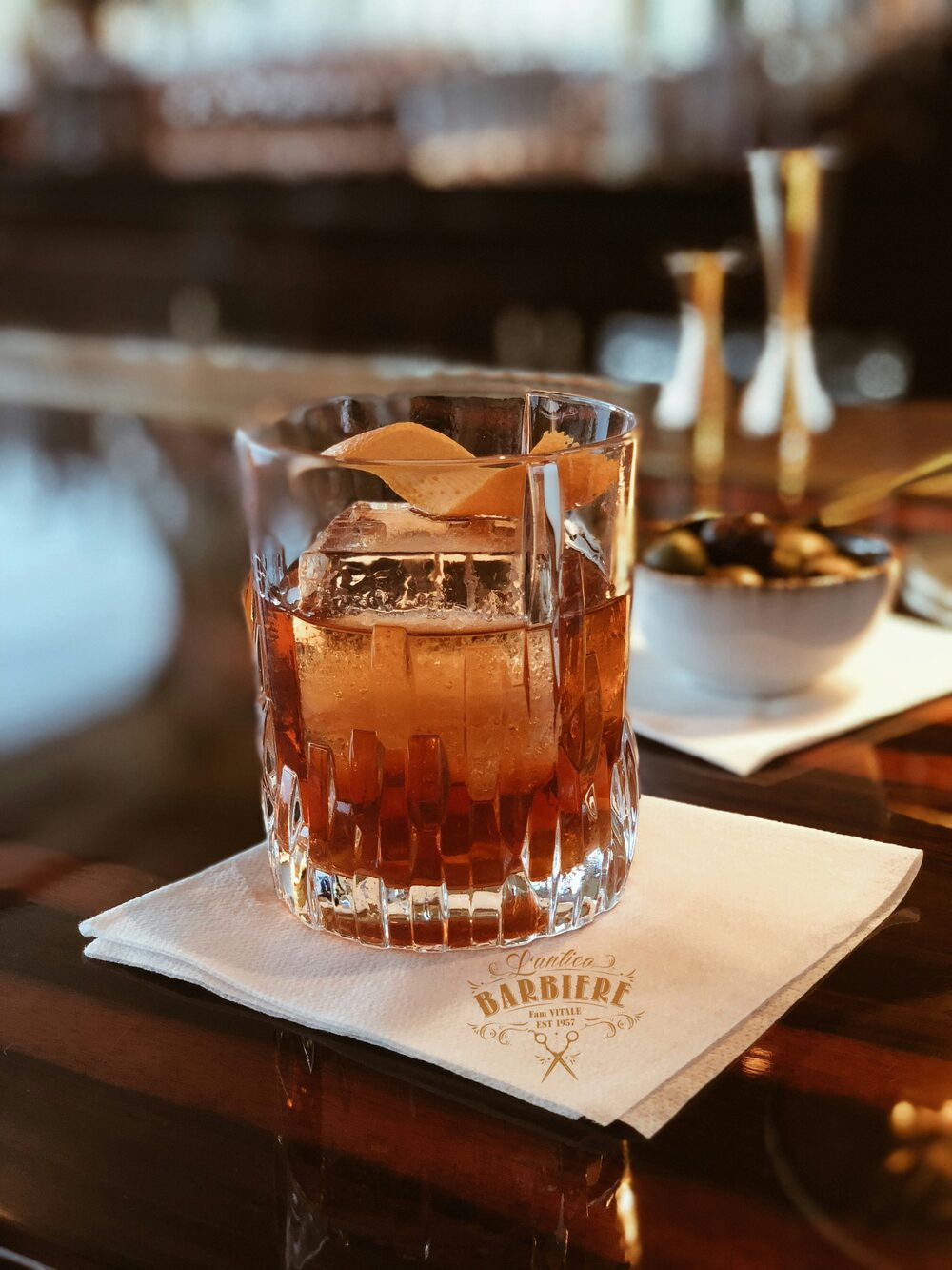 Old Fashioned im Kristallglas auf einer Serviette mit dem L'antico Barbiere Logo