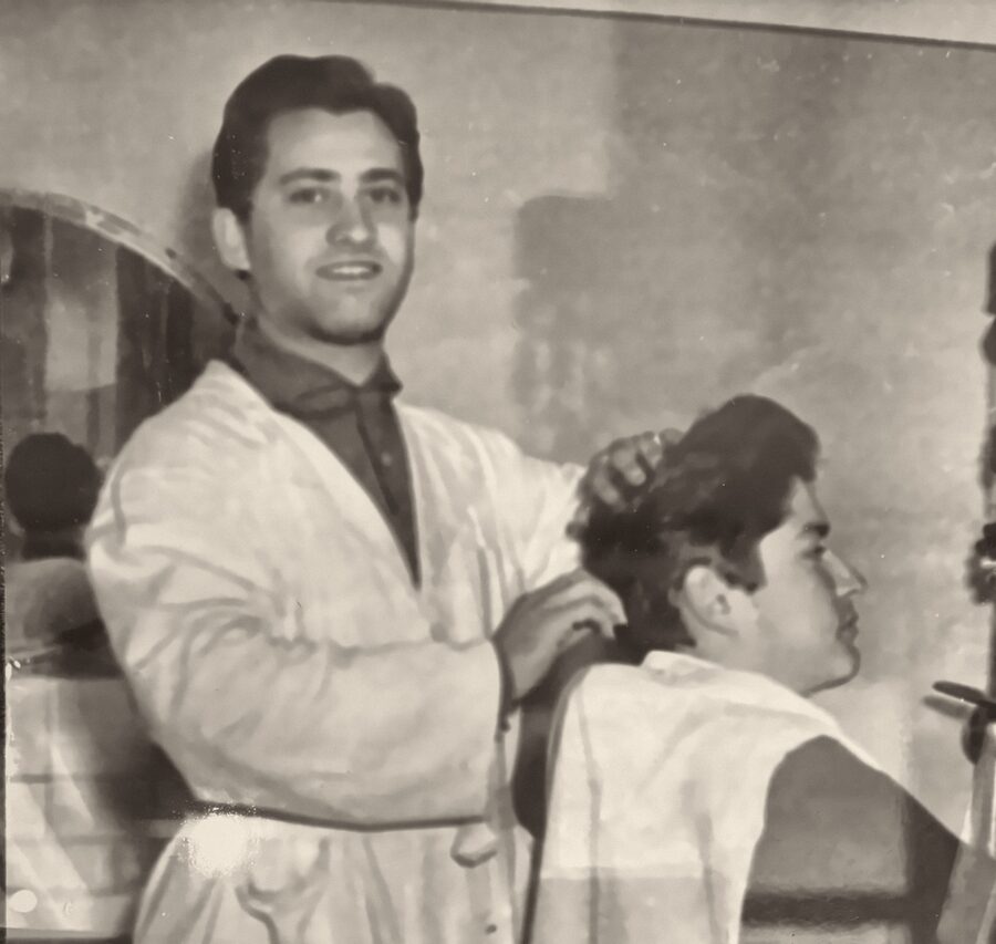 Danieles Grossvater im weissen Kittel bei einem Kunden in seinem Barbershop in Rom, 50er-Jahre
