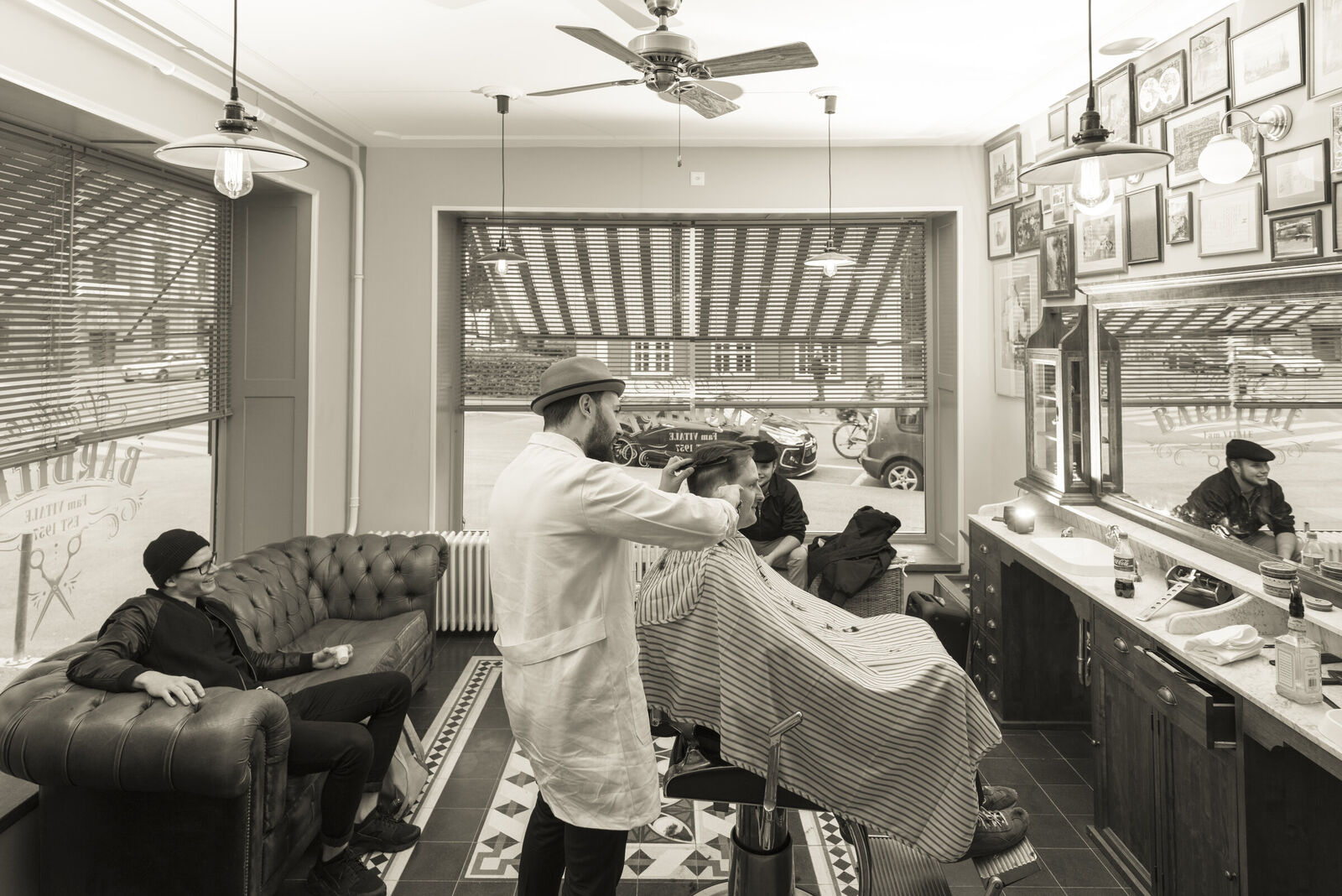 Der Salon von innen mit Barberstuhl, Bilderwand und Marmor-Waschtisch